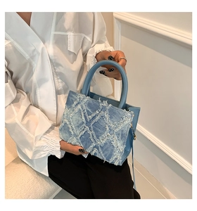 Detail of light blue denim tote with quilted frayed fringe and gold-tone hardware