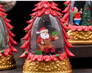 Close-up of Santa Claus snow globe within a red Christmas tree on a golden base