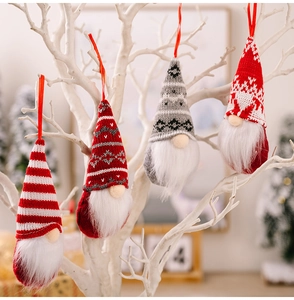 Close-up of knitted Christmas gnomes hanging on white branches with festive warm lighting
