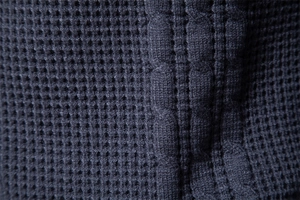 Macro shot of dark grey waffle knit texture showing detailed fabric weave fibers