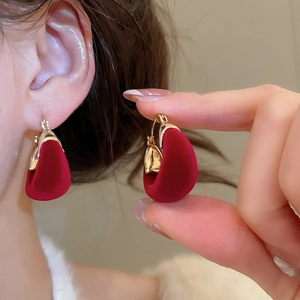 Close-up of a red flocking petal earring held by a model for a vintage look