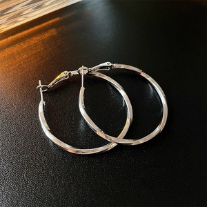 Detail view of large silver hoop earrings with a polished mirror finish on black leather