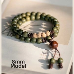 Detail of 8mm green sandalwood prayer beads with yellow accents on vintage book