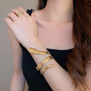 Macro shot of gold snake-shaped wrap bracelet and matching ring set with scale texture