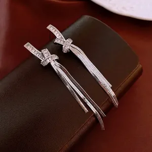 Elegant silver knot tassel earrings with sparkling cubic zirconia on dark leather
