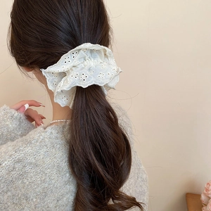 Close-up of a large white lace scrunchie with floral embroidery on a ponytail