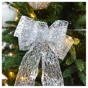 Macro detail of large silver sequin mesh Christmas tree topper bow with festive lighting