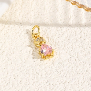 Macro shot of a gold-plated hat character pendant with pink heart-shaped gemstone inlay