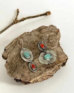 Vista detallada de pendientes étnicos asimétricos con metal plateado martillado y piedras