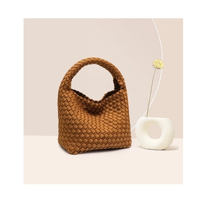 Detailed view of woven texture and handle on a brown bucket bag with a soft silhouette