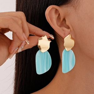 Gros plan d'un mannequin portant des boucles d'oreilles pendantes en acrylique bleu clair