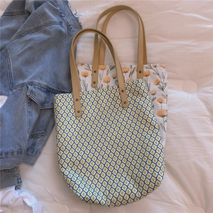 Détail de sacs fourre-tout en toile à motifs avec des poignées en cuir renforcées