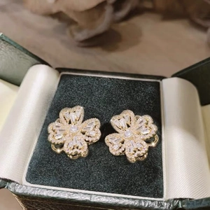 Macro view of gold clover earrings with zircons in a dark green jewelry box