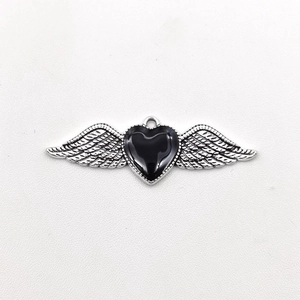 Detail of gothic silver wing pendant encircling a black heart-shaped gemstone jewel