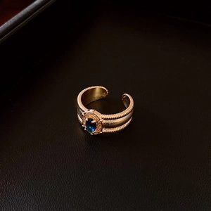 Détail macro d'une bague dorée vintage avec pierre ovale bleue et cristaux pavés