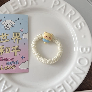 Gros plan d'un chouchou crème avec breloque ours sur une assiette en céramique blanche