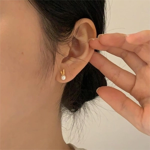 Detail view of 925 silver rabbit pearl earrings worn by a model in warm light