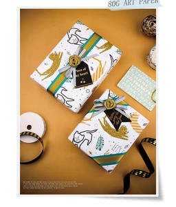 Detail of leopard print gift wrapping paper with metallic gold ink and tropical leaves