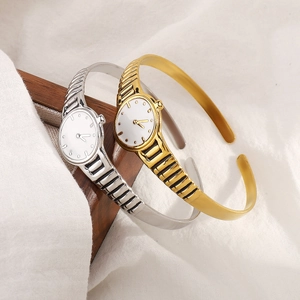 Creative watch-style open cuff bracelet in gold and silver finish on a display