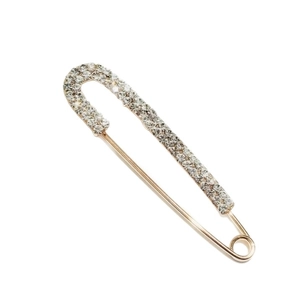 Elegant gold-tone safety pin brooch with sparkling white rhinestones on white background