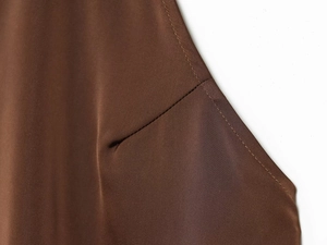 Détail de couture en dentelle sur un haut dos nu marron foncé en tissu polyester lisse