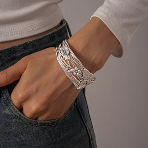 Detailed close-up of wide silver cuff bracelet with butterfly and floral engravings