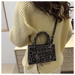 Dettaglio mini borsa a tracolla leopardata con manici intrecciati e accenti di frange