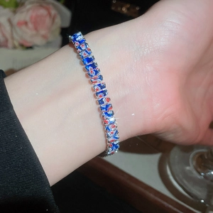 Gros plan d'un bracelet vintage en argent avec des motifs floraux bleus et rouges