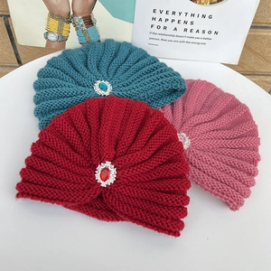 Detail of knitted winter beanies with large gemstones in burgundy, blue and pink colors