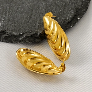 Golden shell design stainless steel earrings with textured surface on a black stone base