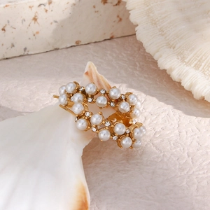 Macro detail of gold-plated hoop earrings with inlaid pearls and zircon on a shell base