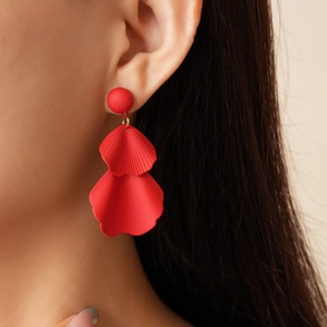 Close-up of red petal drop earrings with gold rings on model's ear for resort style