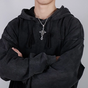 Close-up of a silver gothic cross skull pendant on a black hoodie for a street style look