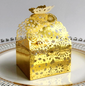 Detail of laser-cut gold wedding favor box with butterfly top and floral rose patterns