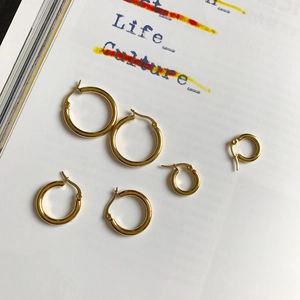 Detailed view of three pairs of gold-plated stainless steel hoop earrings in different sizes