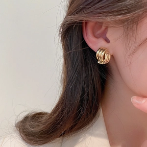 Close-up of golden multi-loop geometric earrings on a model showing chic metal texture