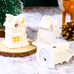 Detail of white resin miniature Christmas house with glowing lights on snowy base decor