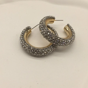 Close-up of gold pave hoop earrings featuring shimmering clear rhinestones and C-shape design