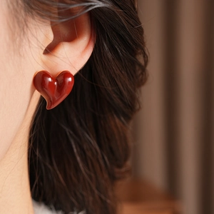Close-up of elegant red heart-shaped earrings with gold plating on a model's ear