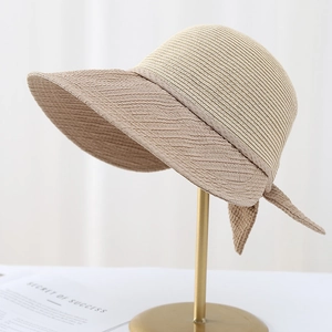 Stylish beige wide-brim straw sun hat with patchwork texture and bow for beach vacation