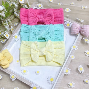 Close-up of three nylon baby headbands with bows in rose, mint green and pale yellow