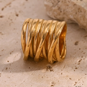 Close-up of a wide multi-layer 18K gold plated wrapped ring on a stone surface