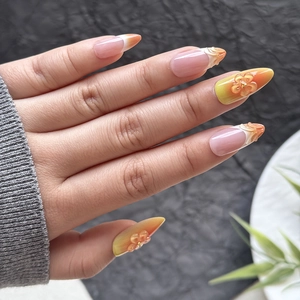 Detail of gradient orange press-on nails with 3D embossed flowers and white French tips