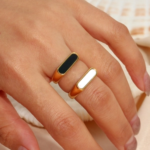 Close-up of minimalist gold-plated stainless steel rings with black and white rectangular faces