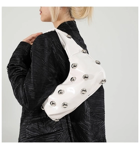 Detail of white glossy patent leather shoulder bag with silver spherical rivets and strap
