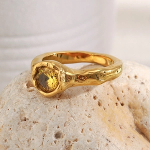 Detail of 18K gold plated stainless steel ring with yellow zircon on natural stone