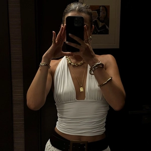 Close-up of a white halter neck top with deep V-neck and layered gold jewelry accessories
