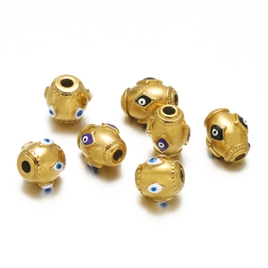 Close-up of golden stainless steel evil eye beads with colorful enamel on white background