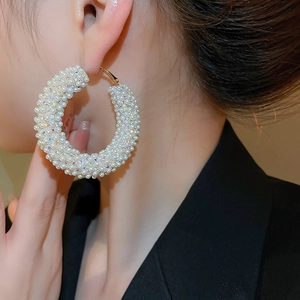 Macro detail of luxury hoop earring with white pearls and sparkling crystals on model