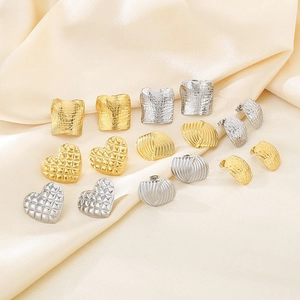 Polished 18k gold and silver heart and geometric stud earrings on beige silk